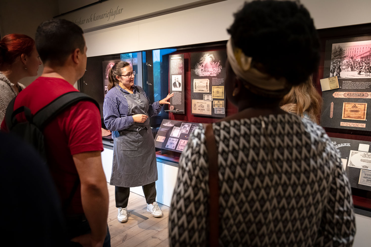 Museipedagog som pekar på föremål bakom en monter