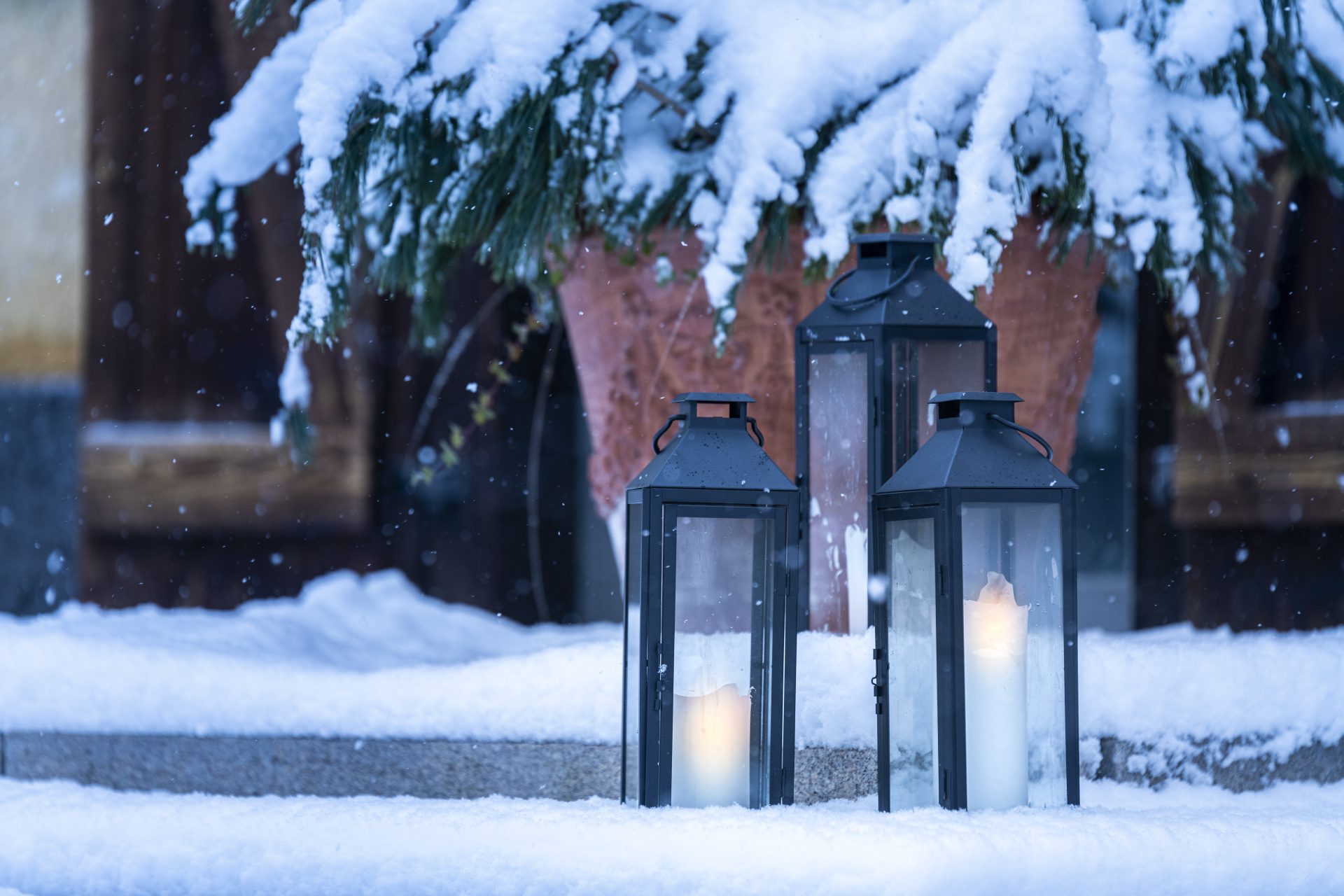 Two lit lanterns on a snowy step. 