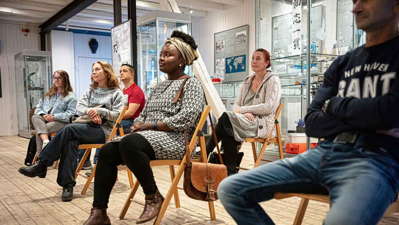  Visitors sitting and listening to a paper workshop in the Red warehouse.