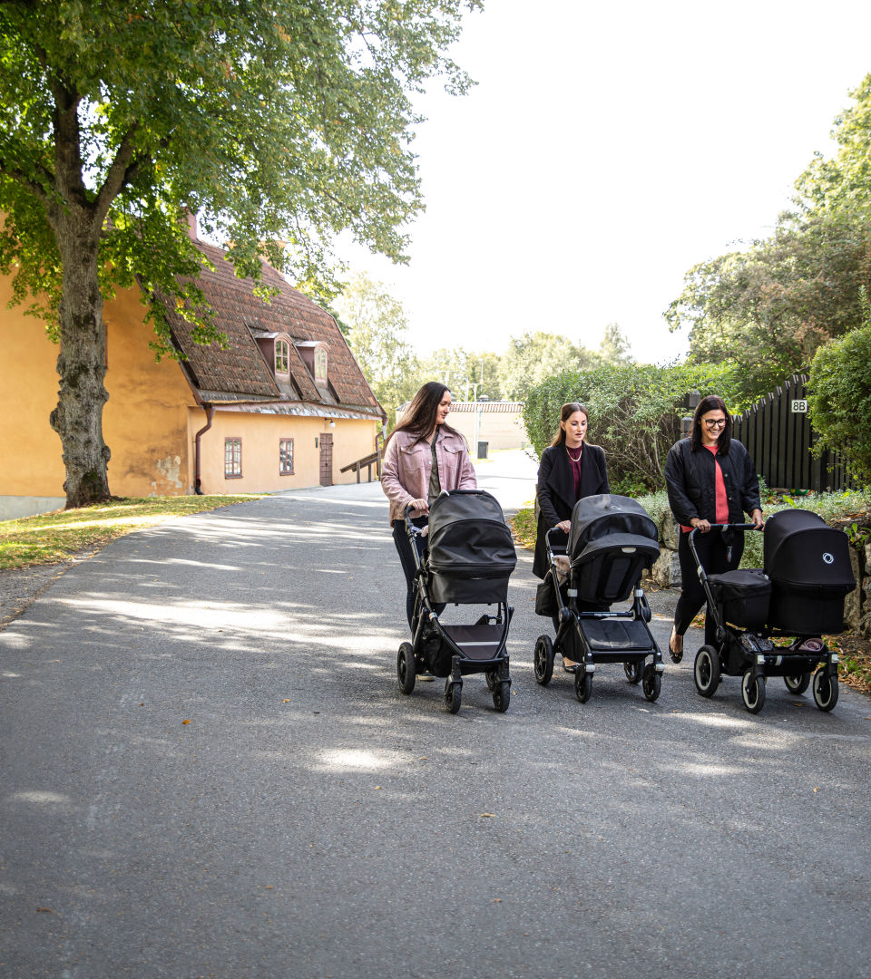 Tre personer med varsinn barnvagn som är ute och promenerar