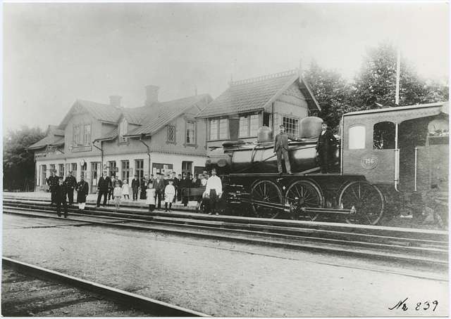 A black and white photograph of men and children standing on train tracks and on a locomotive.
