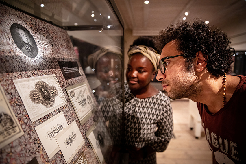 A woman and a man looking at banknotes in a show case.