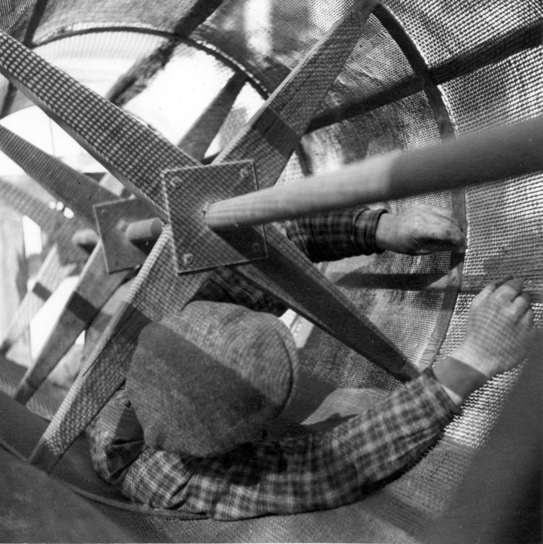 A black and white photo showing a man inside a machine, reparing it.