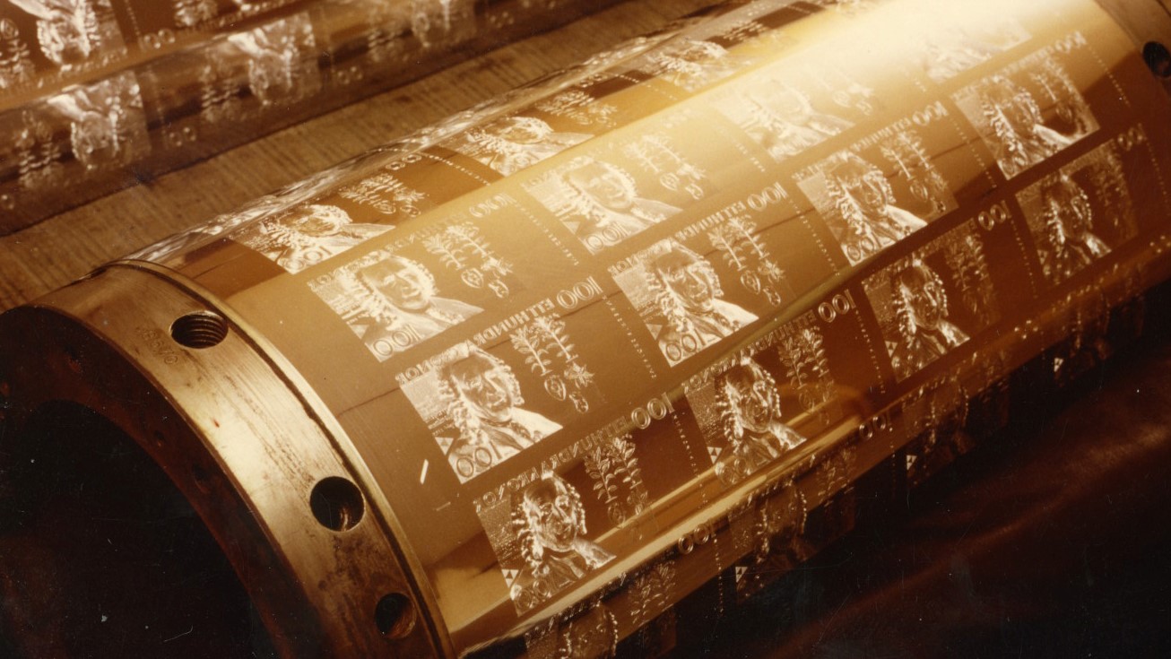 A metal cylinder with etched images of banknotes.