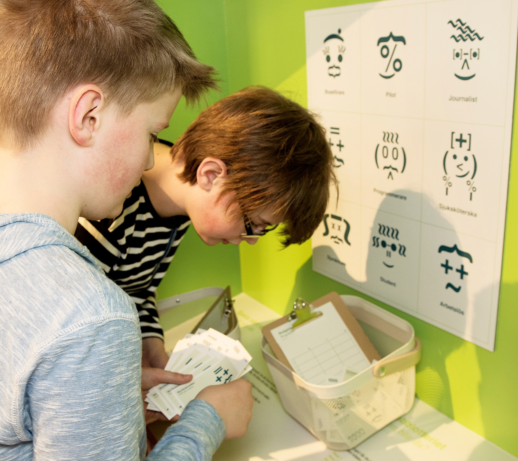 Two children looking down into a basket filled with paper notes.