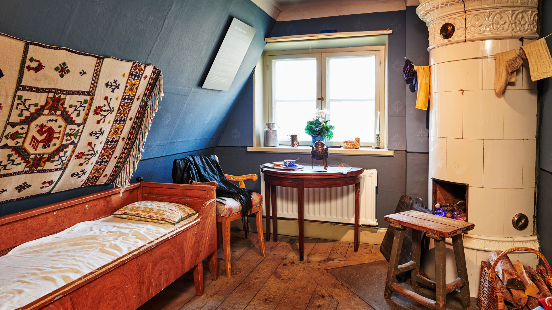 An interior of a bedroom with a bed and a fireplace. 