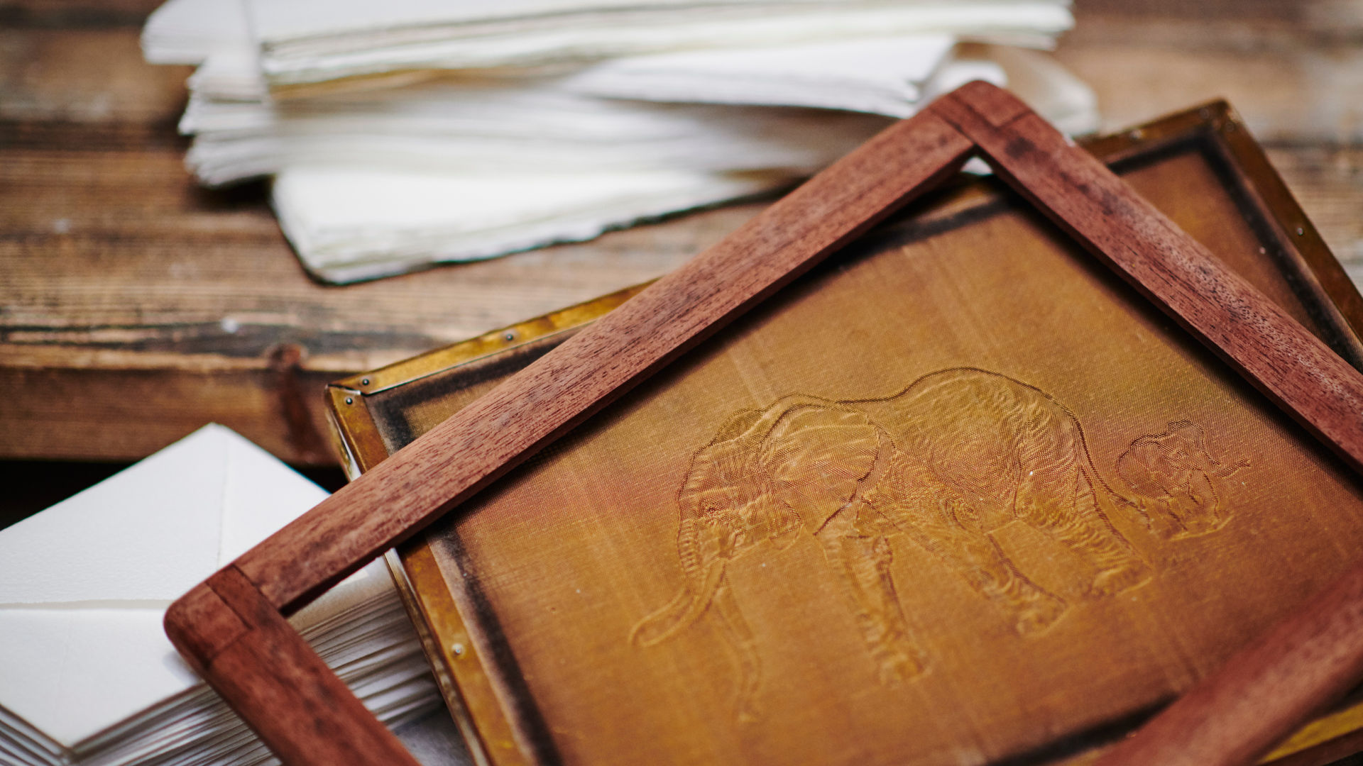 A wooden frame used to make paper with a pattern showing an elephant. 