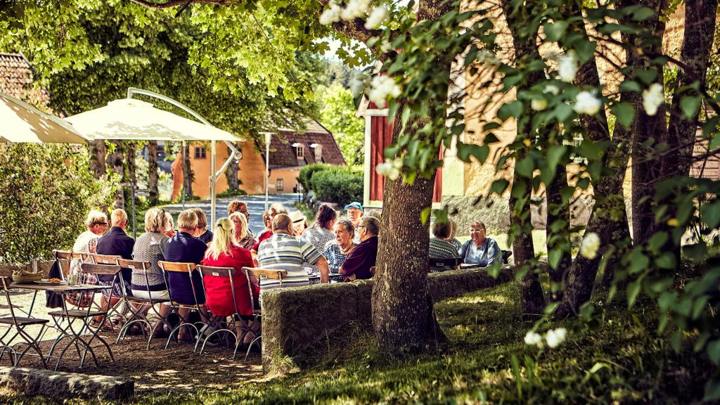 Folk sitter på uteservering under träd
