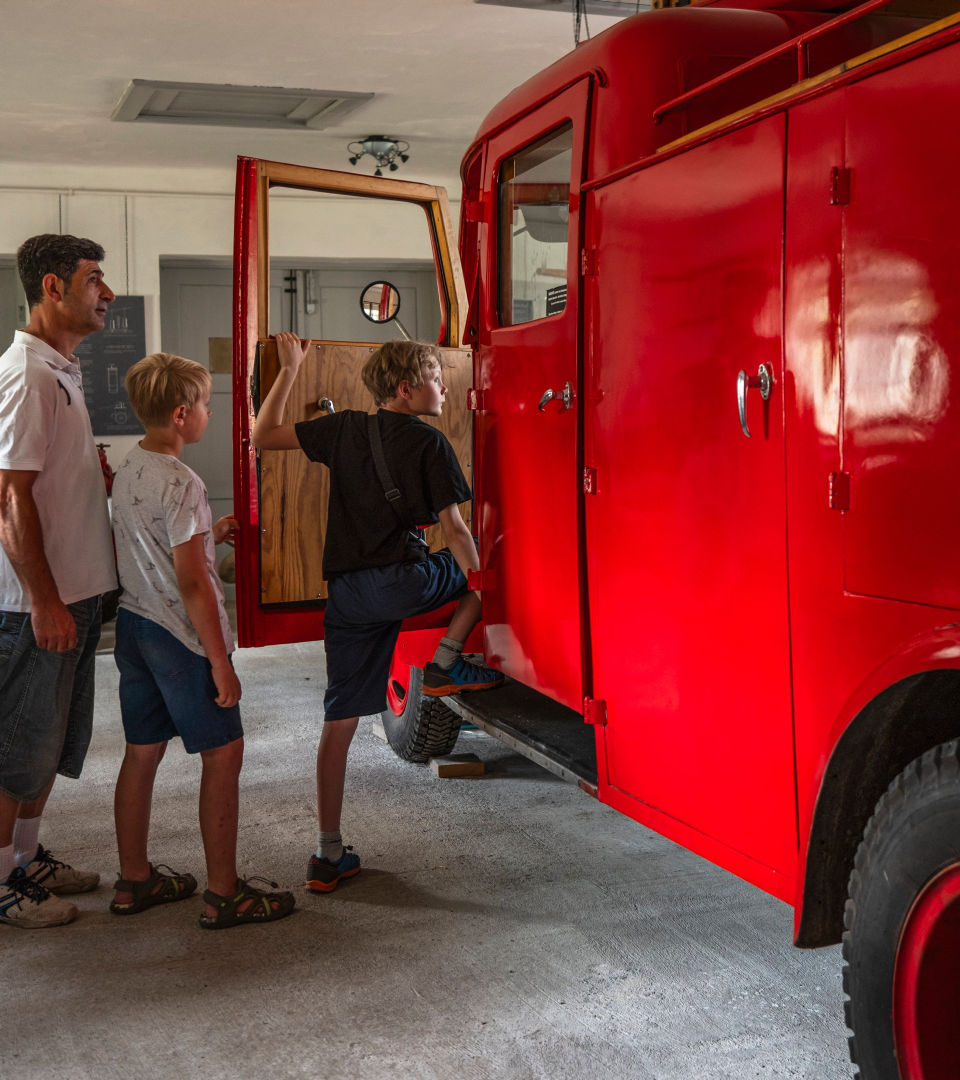 Barn påväg in i brandbilen som står utställd på museet. 