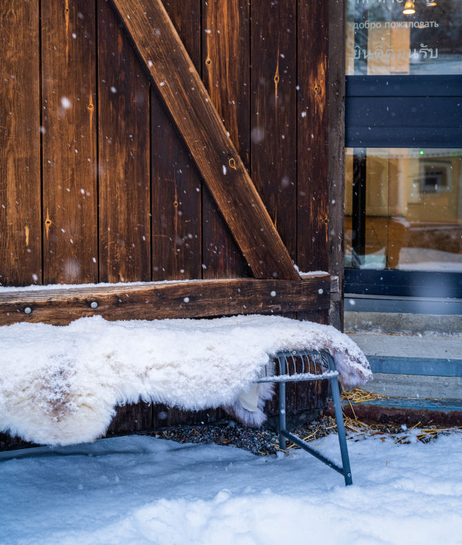 En snöig bänk med fårfäll utanför Tumba bruksmuseum.