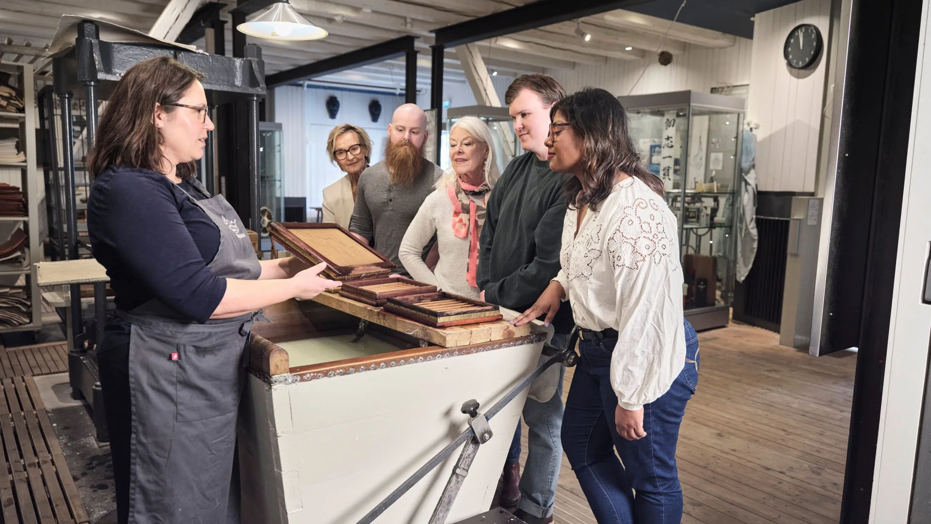 Guide showing a handmade paper and talking about paper making process to visitors.