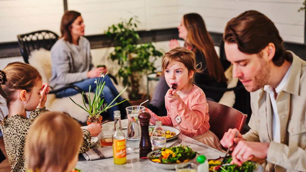 Familj som sitter runt ett bord och äter på caféet.