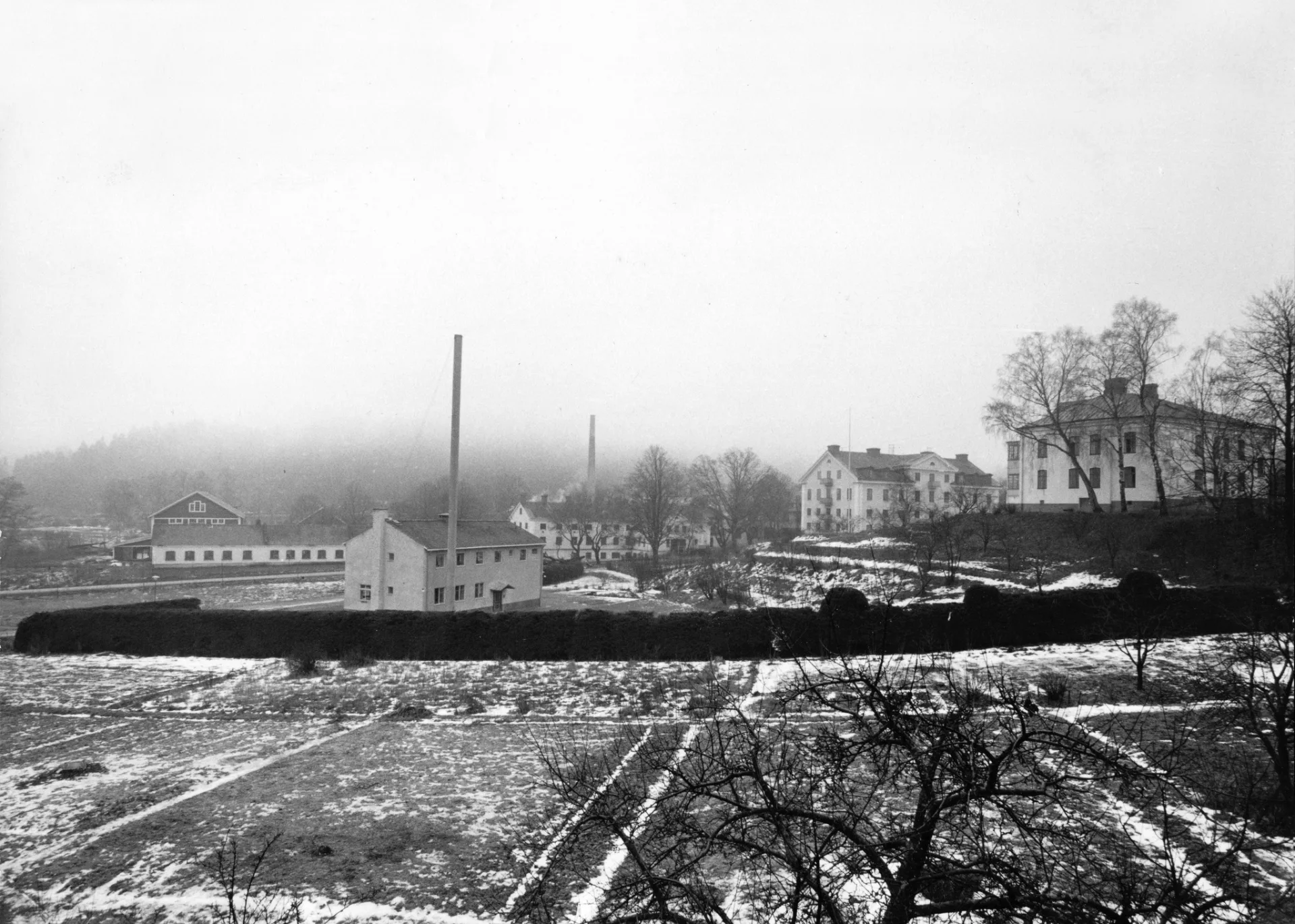 Gammalt svartvitt foto av bruket under vintern