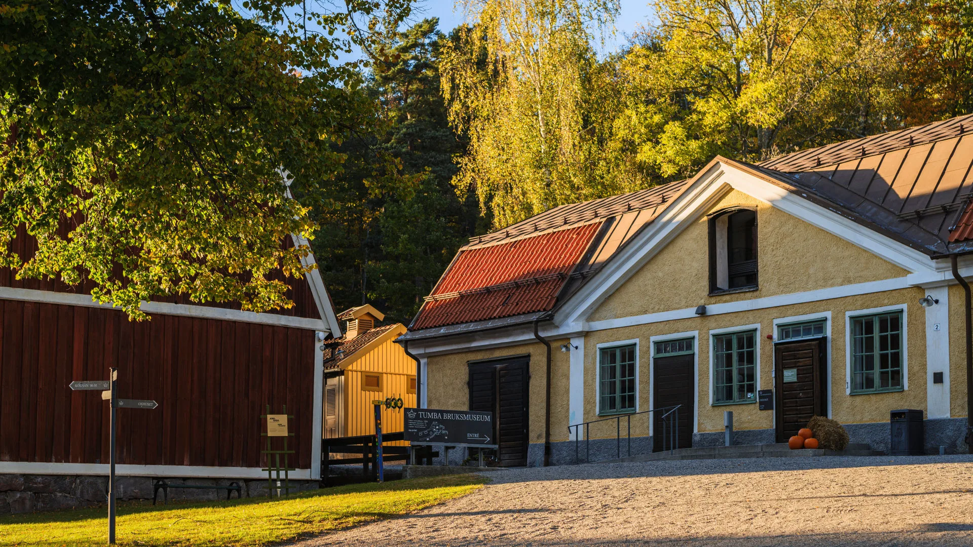 Museets fasad under hösttid med gula, röda och gröna löv i bakgrunden