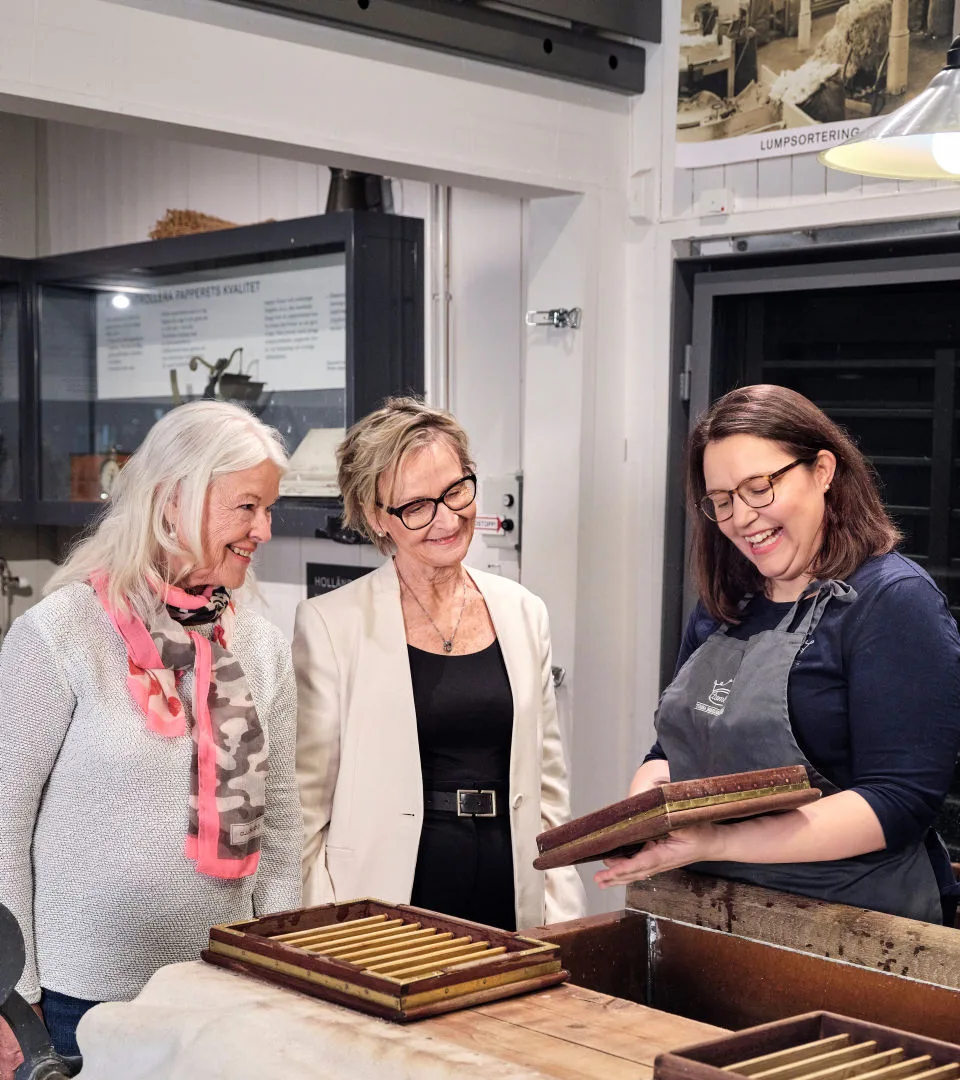 Besökare tittar på en pappersform tillsammans med museipersonal.
